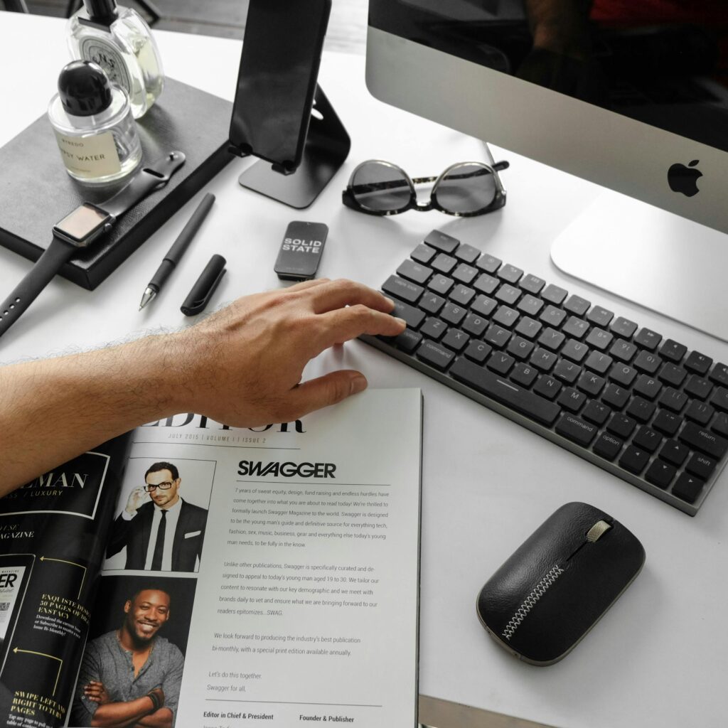 A modern desktop setup featuring tech gadgets and a stylish magazine in an office setting.