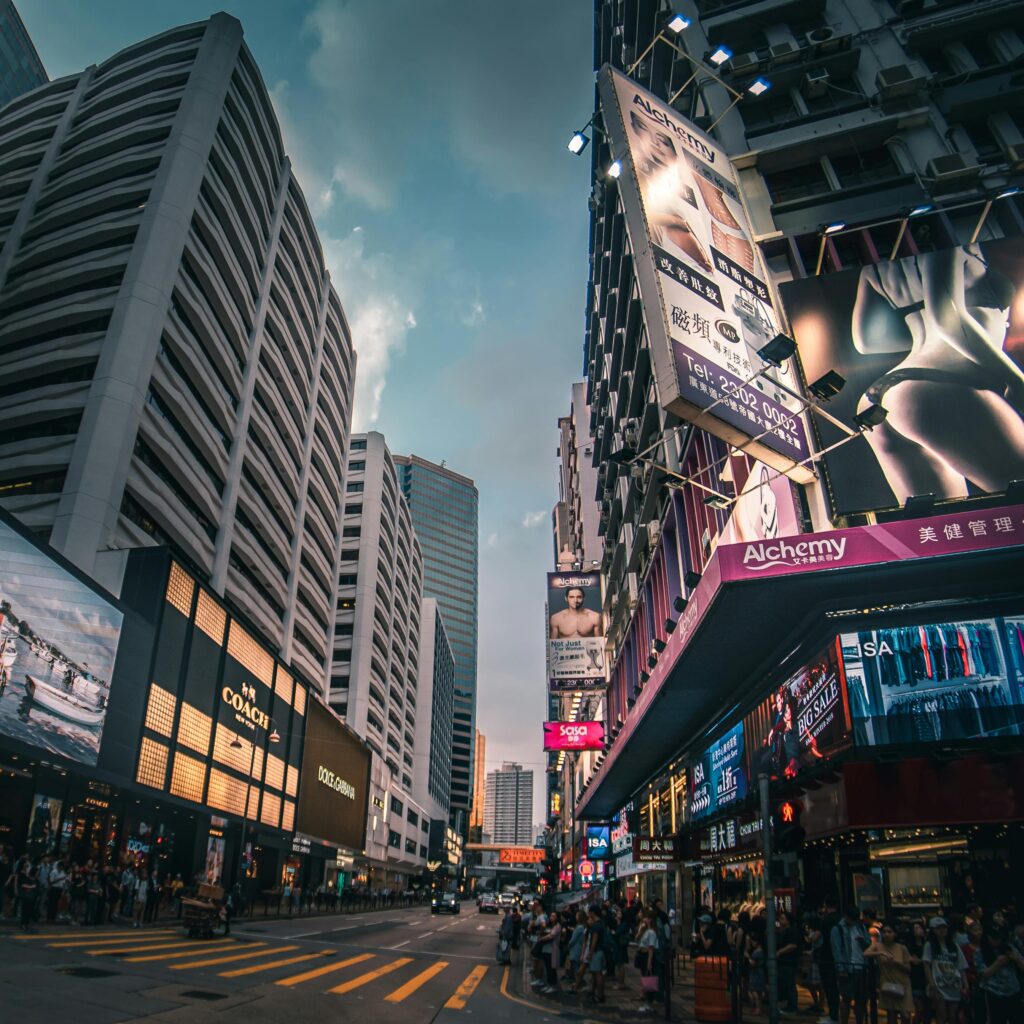 A bustling city street lined with skyscrapers and illuminated billboards at twilight.